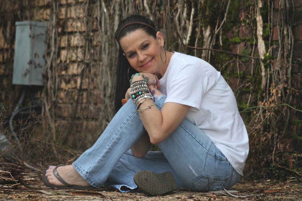 Free Image of Middle Aged Woman sitting outside an old building and smiling for camera 