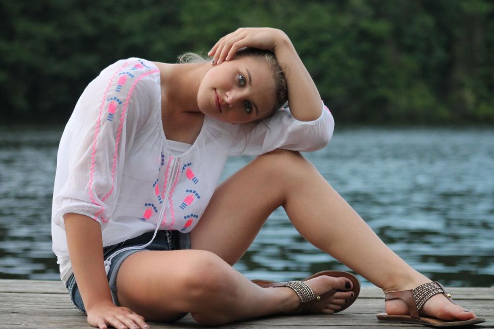 Free Image of Young Woman Sitting on Jetty - Looking at camera 