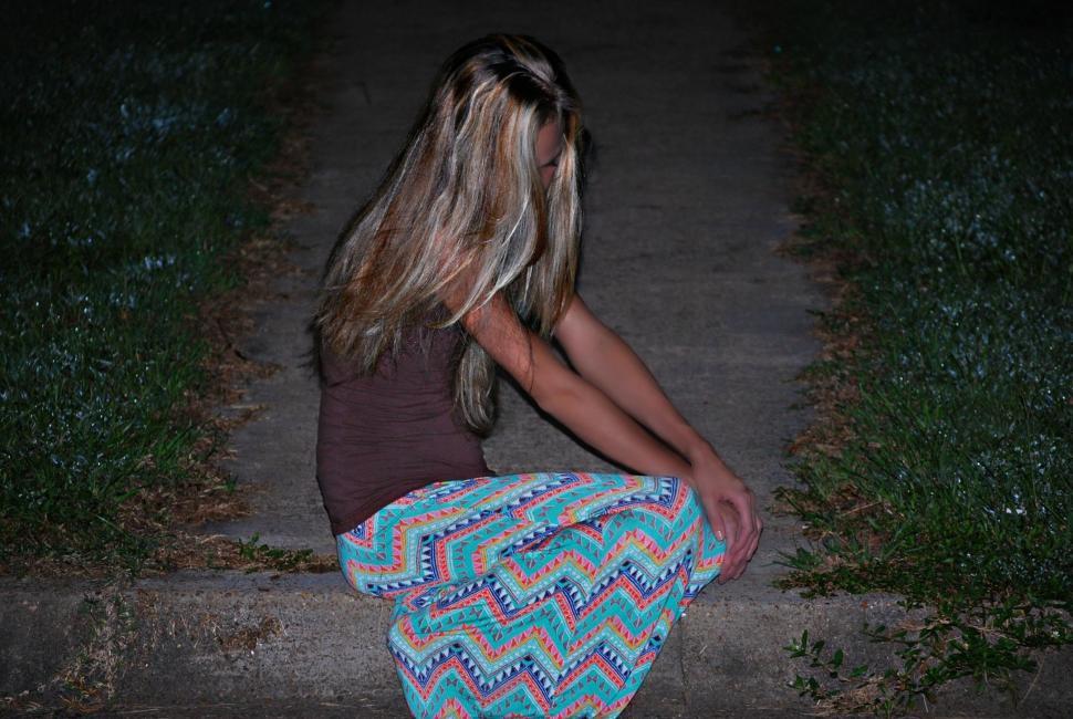 Free Image of Night View of Blonde Woman Sitting on Sidewalk  