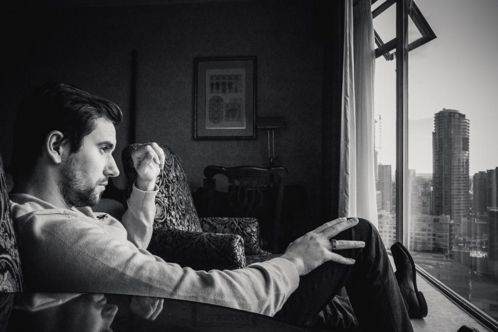 Free Image of Young Stylish Man With Stubble Beard on Chair - looking out from window  