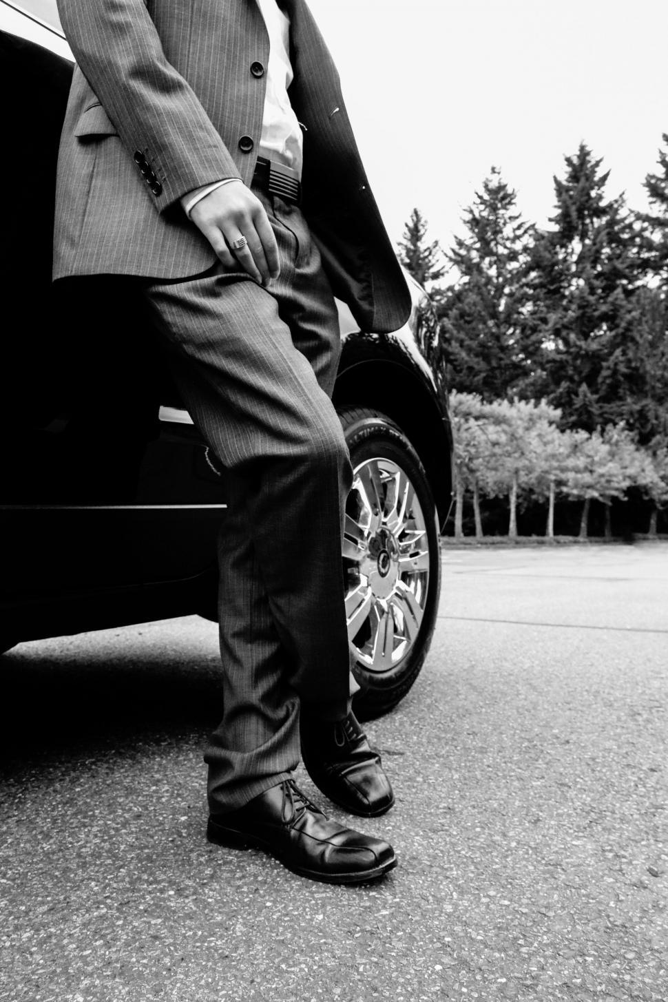 Free Image of Well-dressed Businessman with car at parking lot -B&W 
