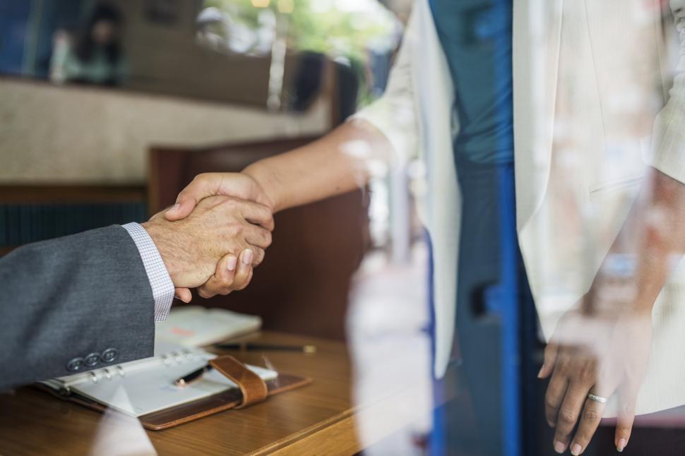 Free Image of Looking through a window at a handshake between two business people 