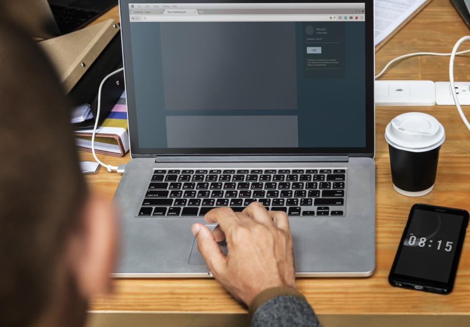 Free Image of A person typing on the laptop with phone and coffee 