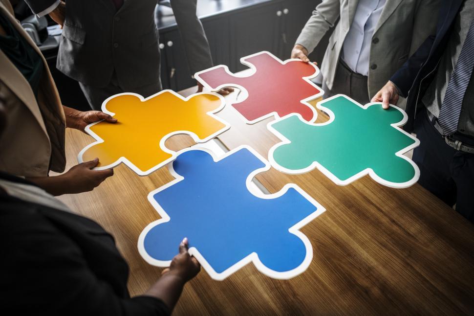 Free Image of A group of colleague joining big colorful jigsaw puzzle cutouts 