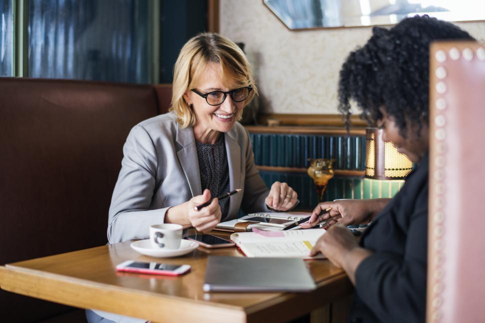 Free Image of Two woman talk at a table in a cafe 