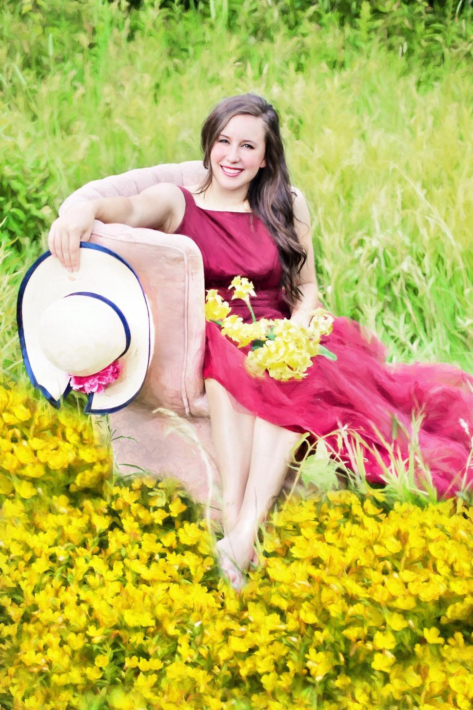 Free Image of Smiling Woman With Flowers And Hat Sitting In Garden 