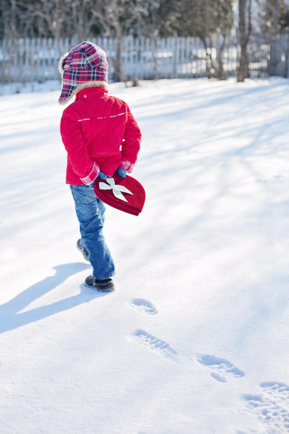 Free Image of Back view of Little Boy with heart box in snow 