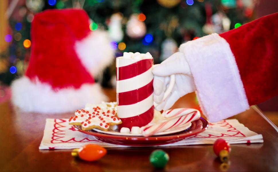 Free Image of Santa Hand and Coffee Mug with colorful bokeh lights 