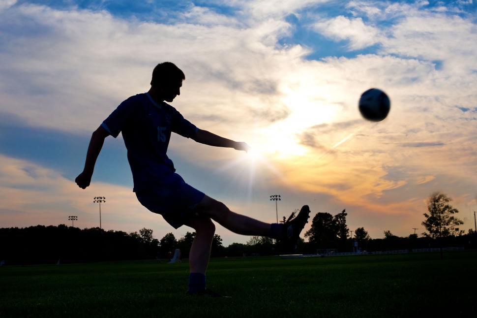 Free Image of Boy playing football in the sunset 
