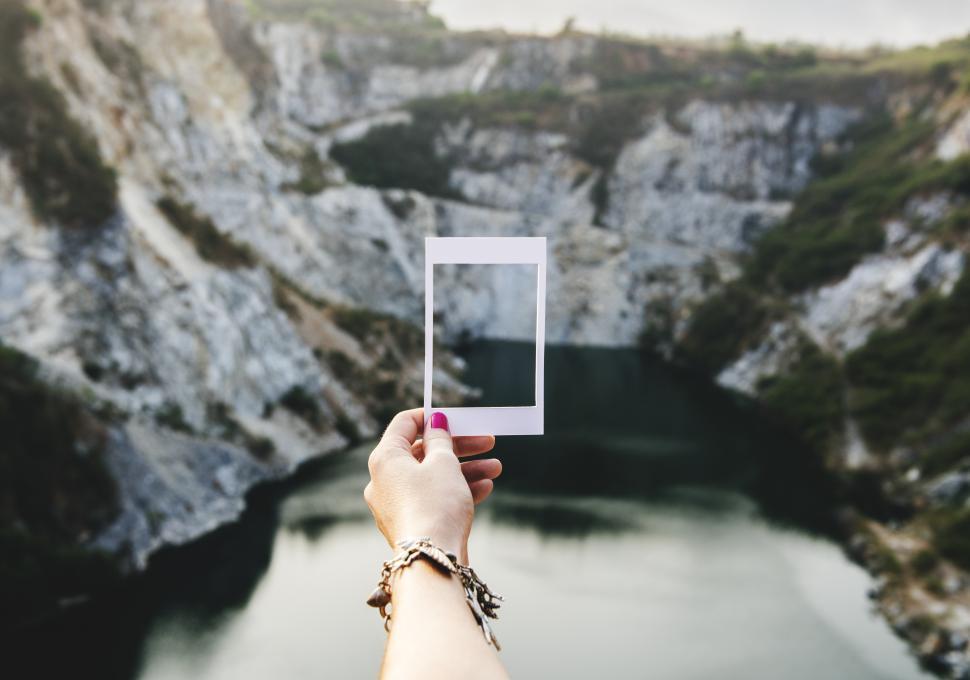 Free Image of Female hand holding a photo frame shaped paper cut out template outdoors 