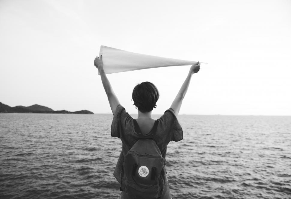 Free Image of A young woman holding white flag high - in black and white 