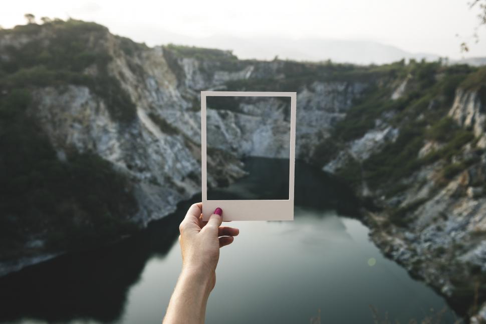Free Image of Holding a photo frame shaped paper cut out in front of landscape 