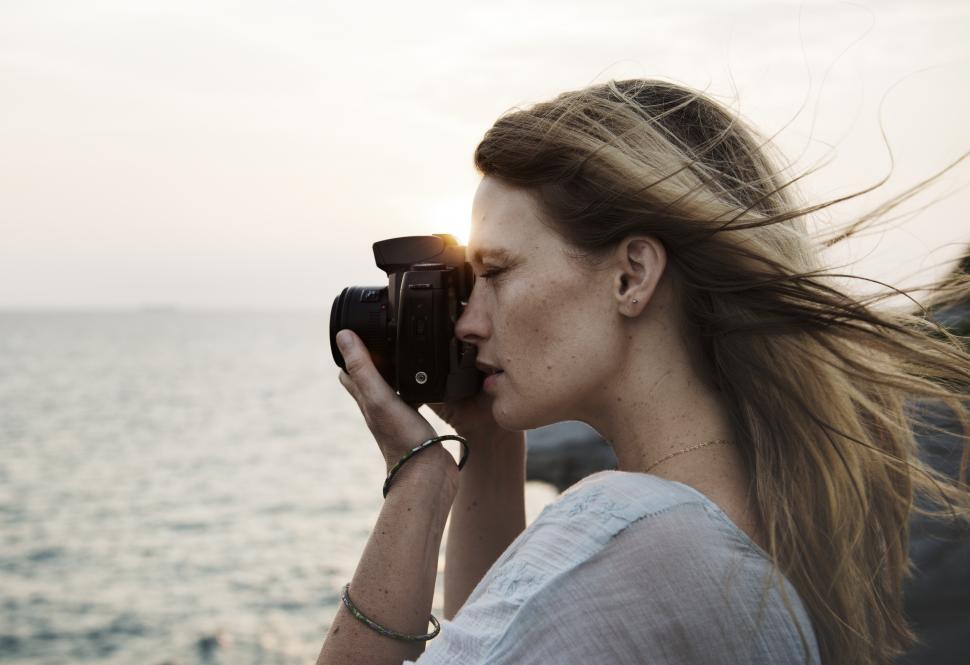Free Image of Side view of a young woman taking photograph at sunset 