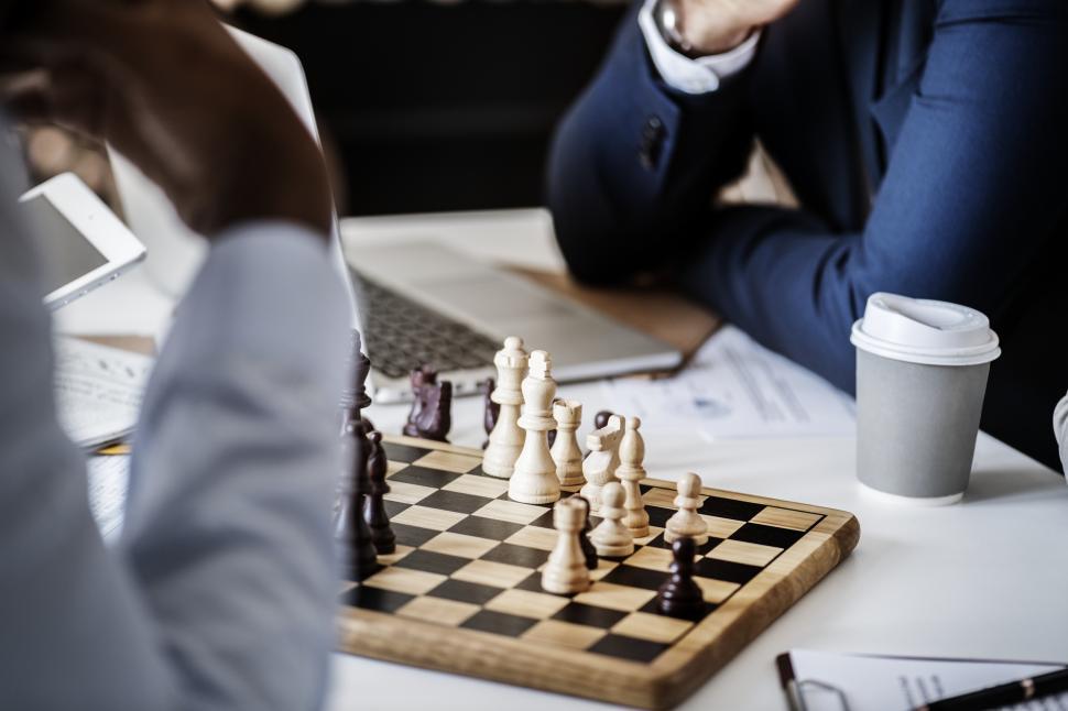 Free Image of Close up of people pondering a chess board 