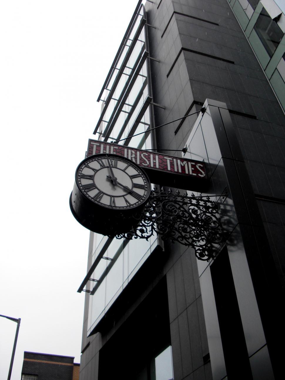 Free Image of Clock Hanging From Side of Tall Building 