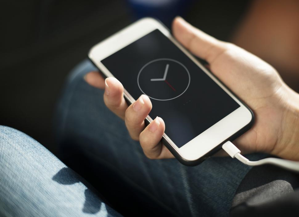 Free Image of Close up a mobile phone in a hand being charged 