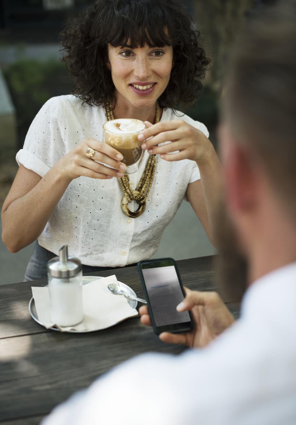 Free Image of Close up of two people having a discussion at an outdoor restaurant table 