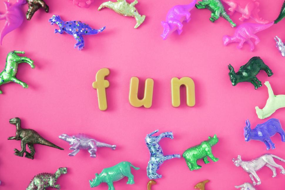 Free Image of Text - fun surrounded with colorful toy animals on pink surface 