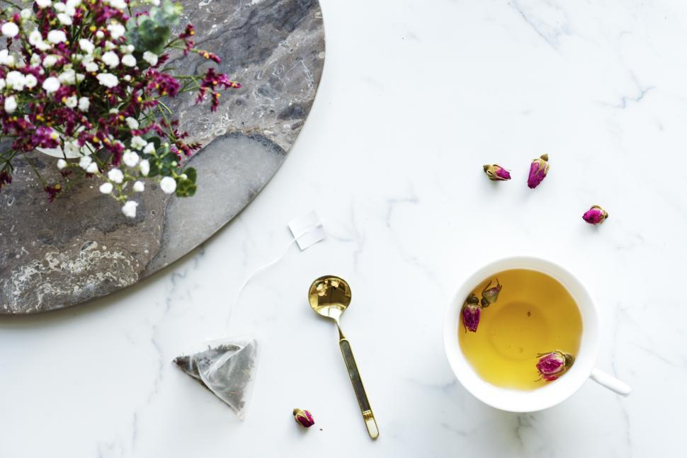 Free Image of Overhead view of a cup of herbal tea alongside flowers - white background 