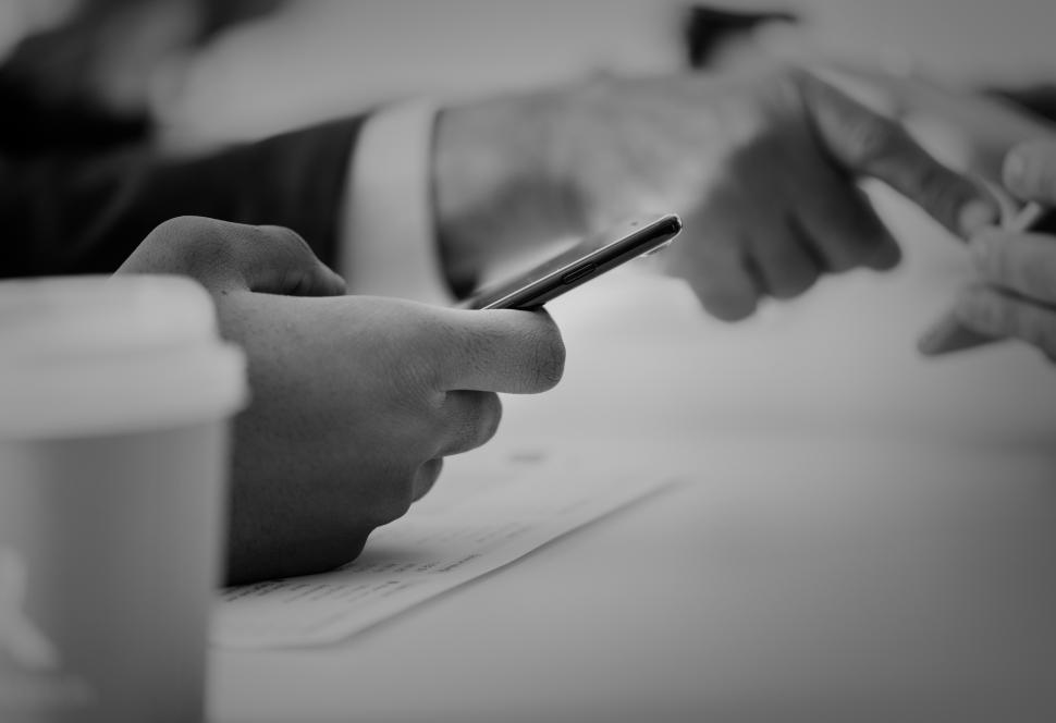 Free Image of Black and white close up of two people holding their mobile phones 