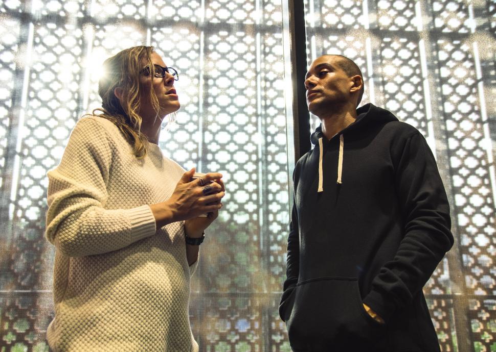 Free Image of A young woman and a man stand and talk at a cafe 