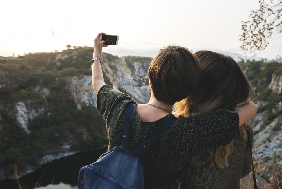 Free Image of Rear view of two young female hikers taking photo with mobile 