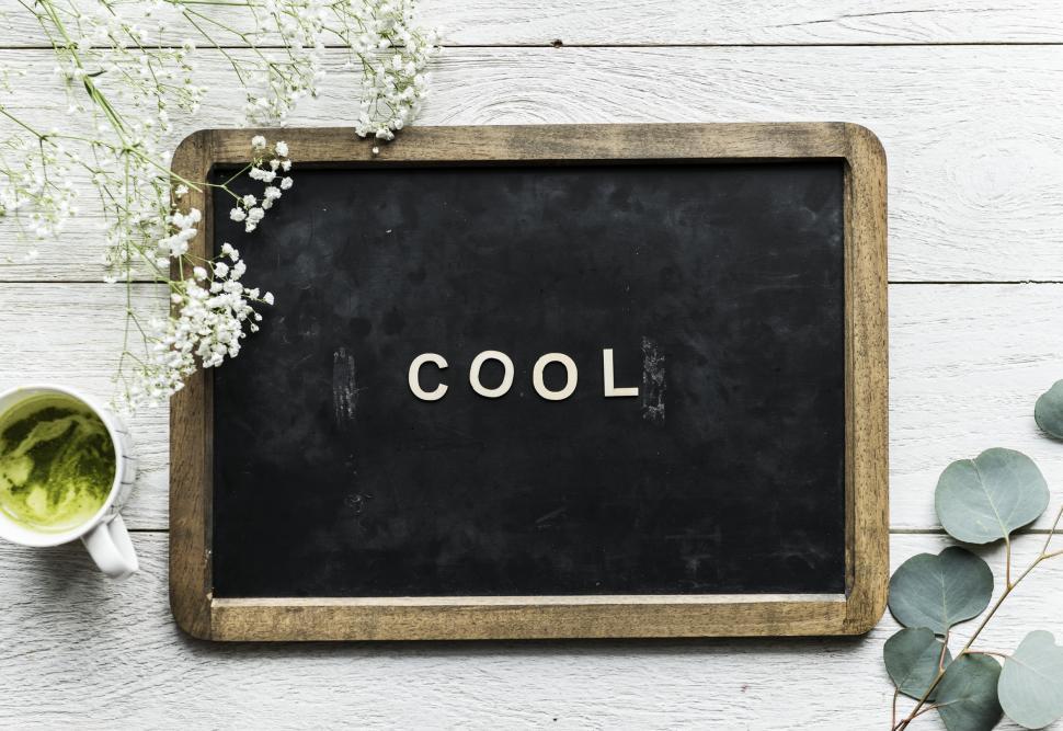 Free Image of Overhead view of the word COOL being written by arranging plastic alphabet blocks on a slate 