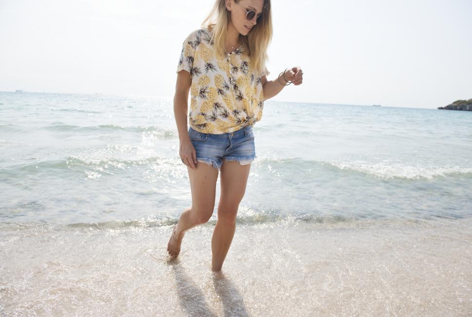 Free Image of A young woman wading on the beach 