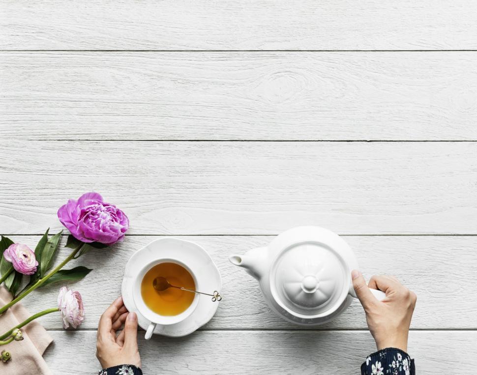 Free Image of Overhead view of a cup of tea alongside a kettle and purple flower 