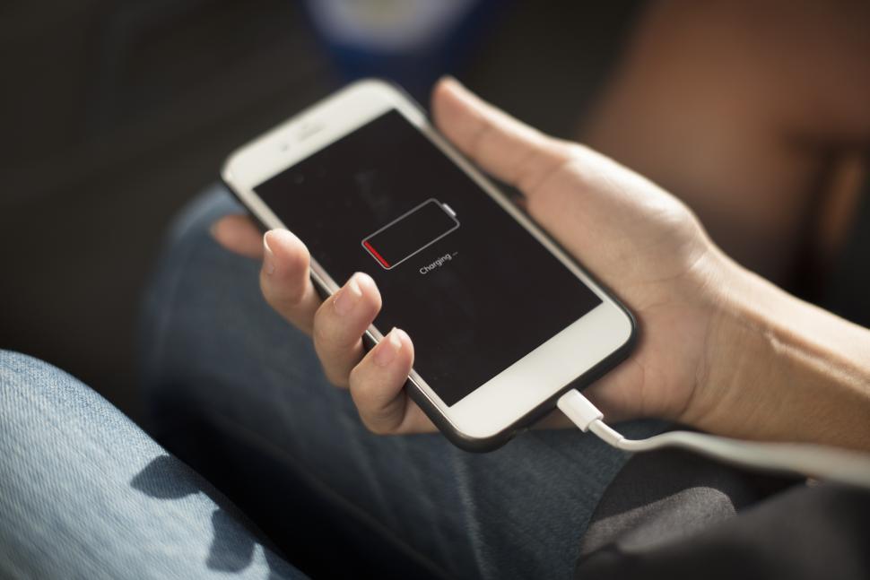Free Image of Close up a mobile phone in a hand being charged 