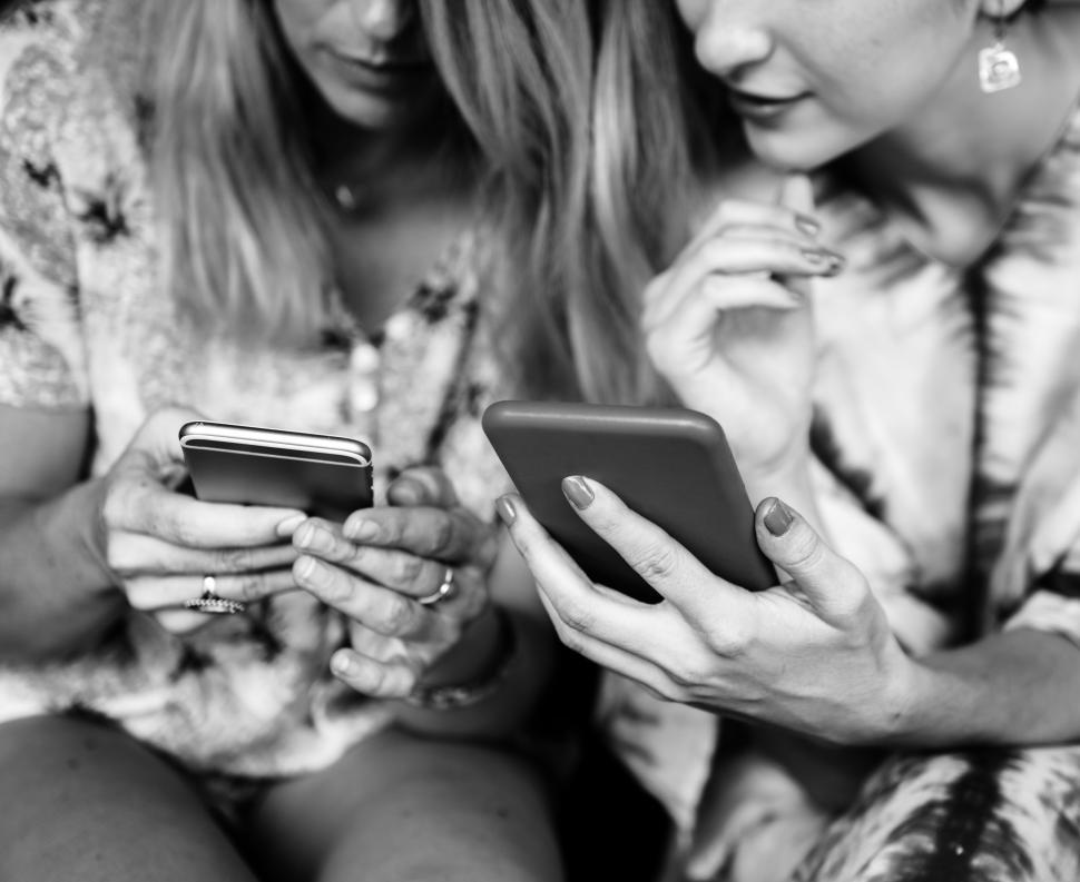 Free Image of Two young Caucasian women posing with their mobile phones 