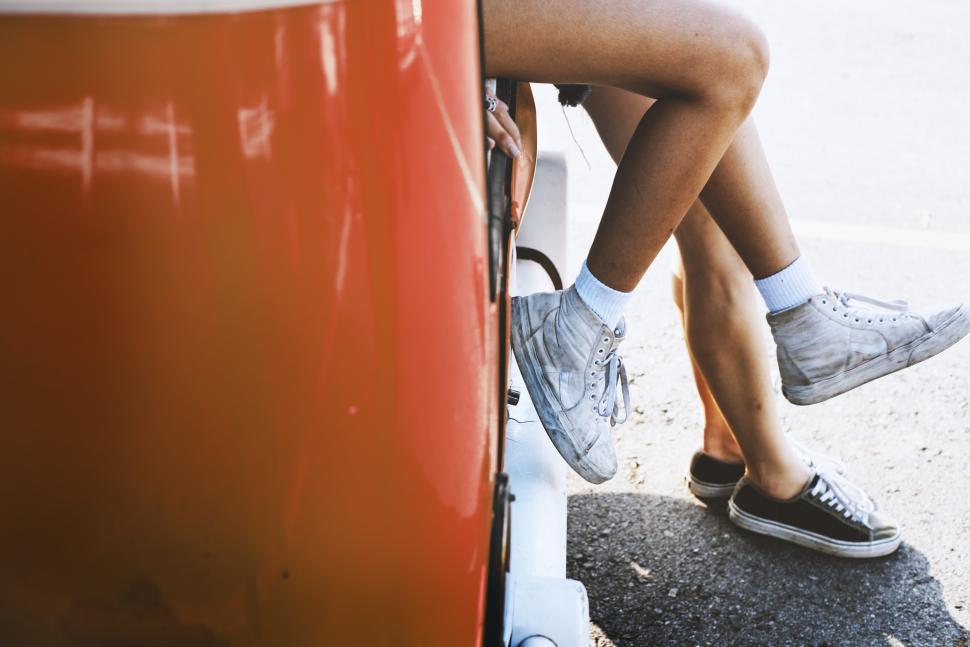 Free Image of Close up of legs hanging out of a van 