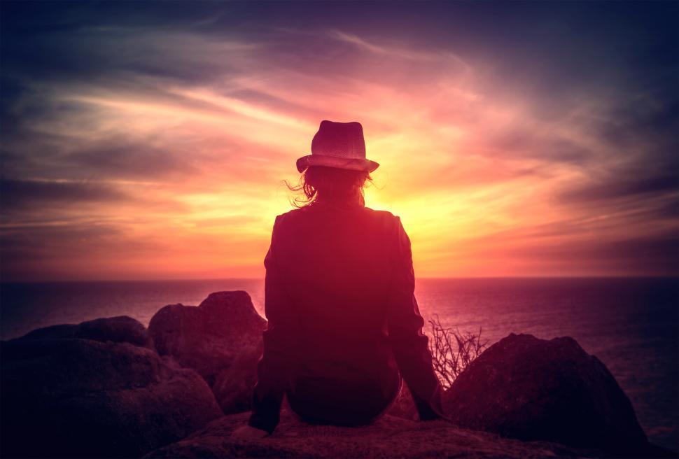 Free Image of Woman Watching the Sunset on Rocky Shore 