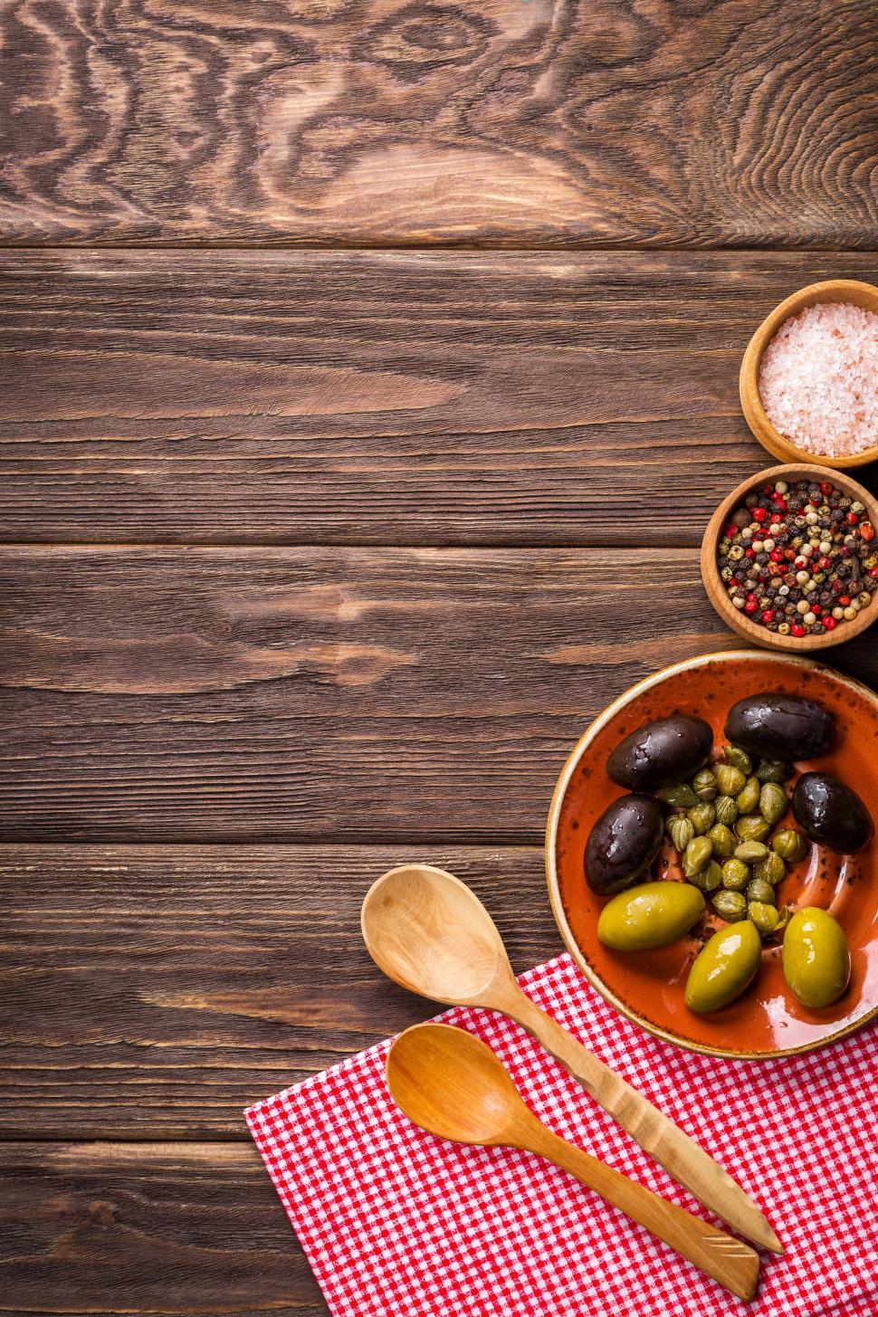Free Image of Overhead view of olives and garlic in a plate on the wooden table 