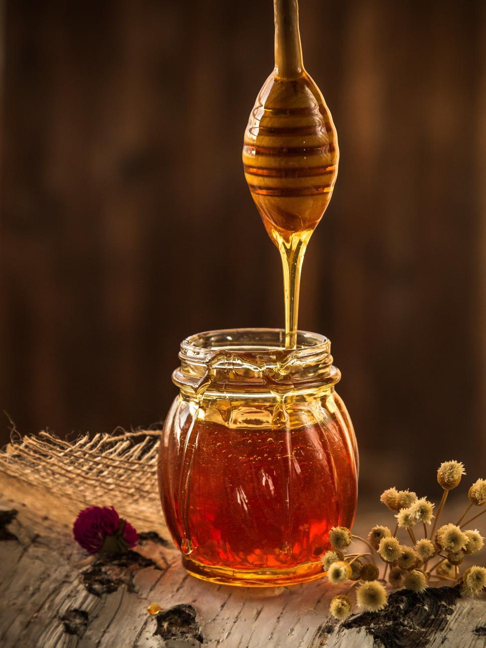 Free Image of Honey dripping from dripper into the glass jar 