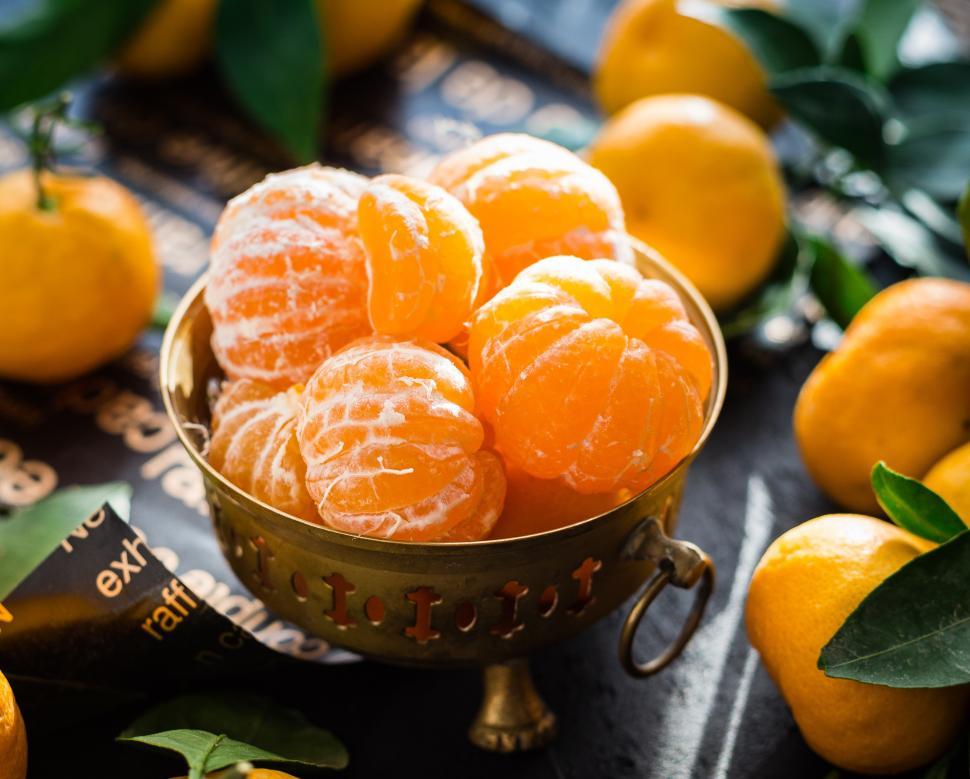 Free Image of Close up of peeled mandarins in a brass fruit bowl 