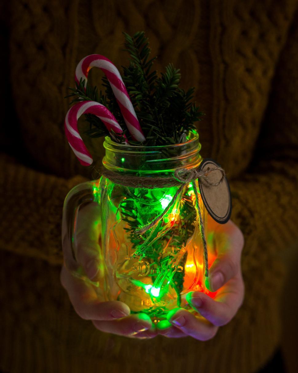 Free Image of Close up of hands holding a mason jar with Christmas decorations 