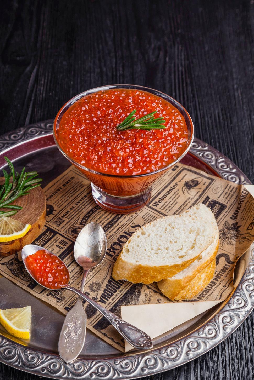 Free Image of Close up of a bowl of red caviar garnished with rosemary leaves 