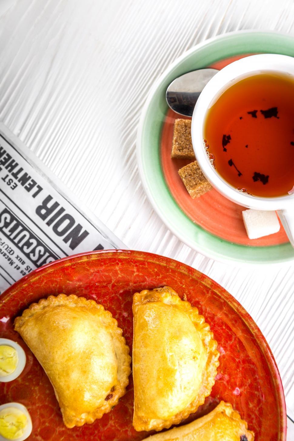 Free Image of Over head view of a cup of tea and Russian pirozhki baked patties 