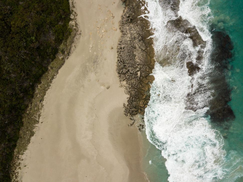 Free Image of Aerial view of ocean waves and empty beach.  