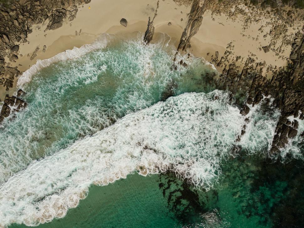 Free Image of Aerial view of ocean waves crashing onto an empty beach.  