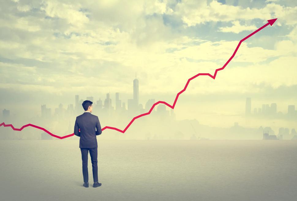 Free Image of Business Growth - Businessman Standing on Rooftop with Upward Ar 