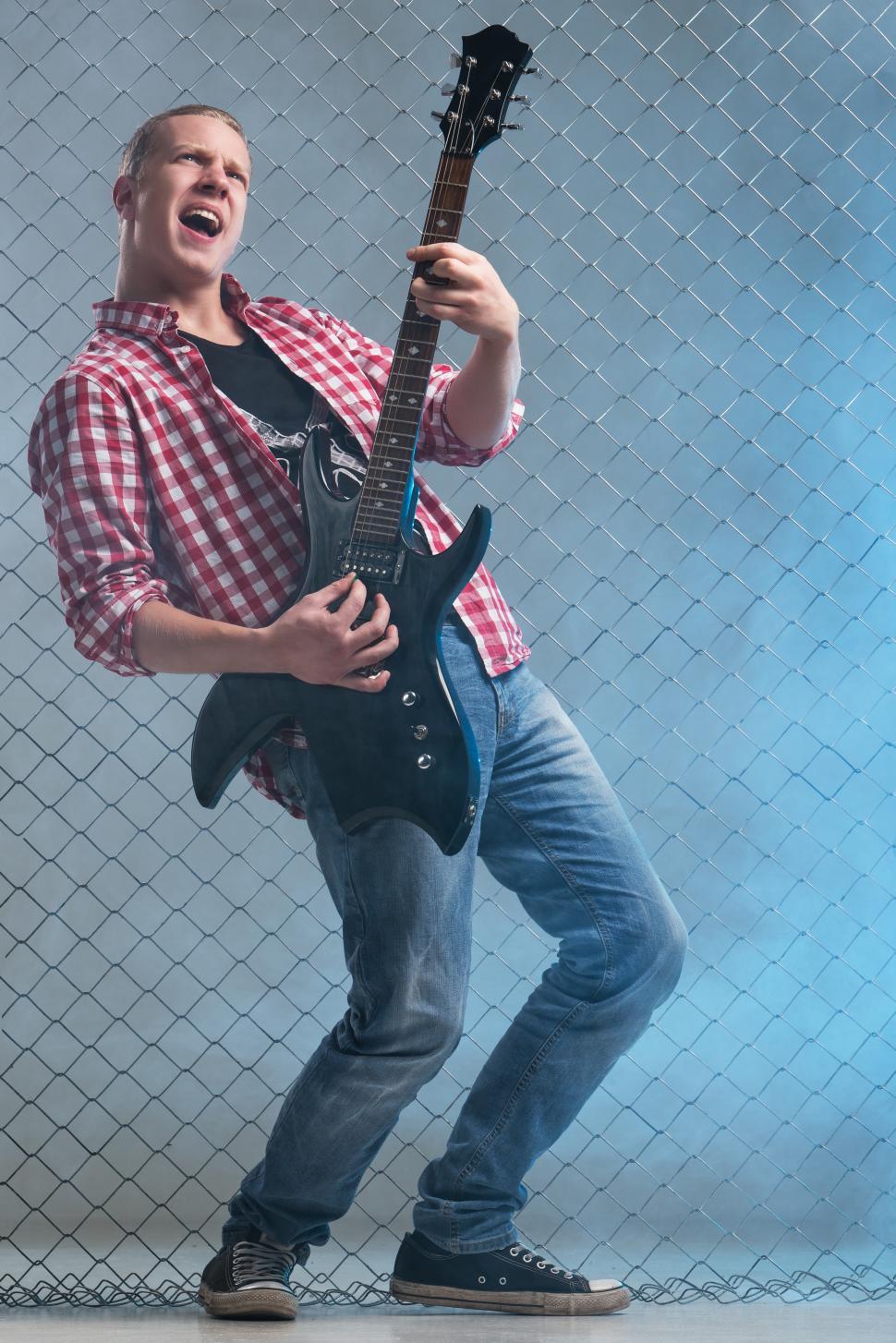 Free Image of Music. Young rock guitar musician on fence background 