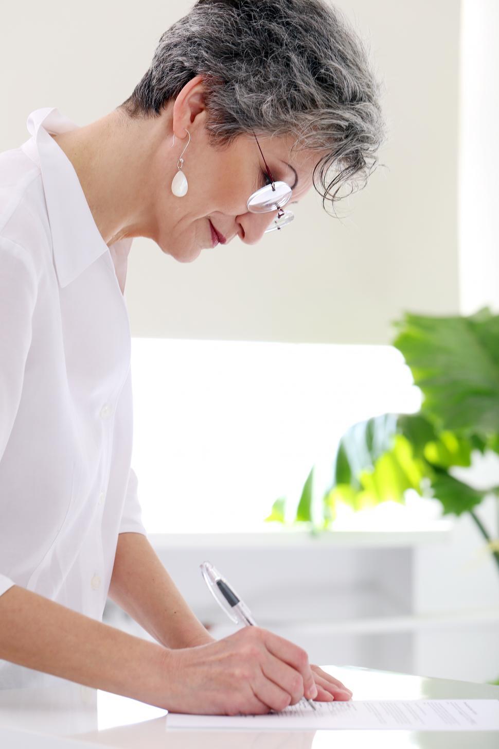 Free Image of Happy mature woman writing 