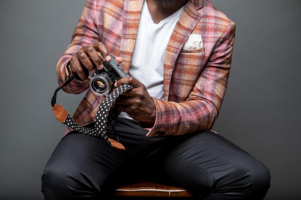 Free Image of Unrecognizable man sitting on chair with retro camera inside a studio 