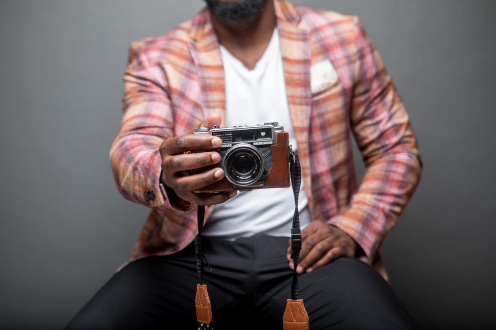 Free Image of Man sitting on chair with vintage camera inside a studio 