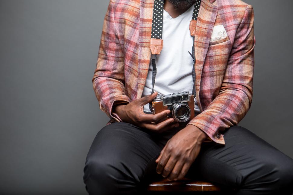 Free Image of Unrecognizable man sitting on chair with retro yashica camera inside a studio 