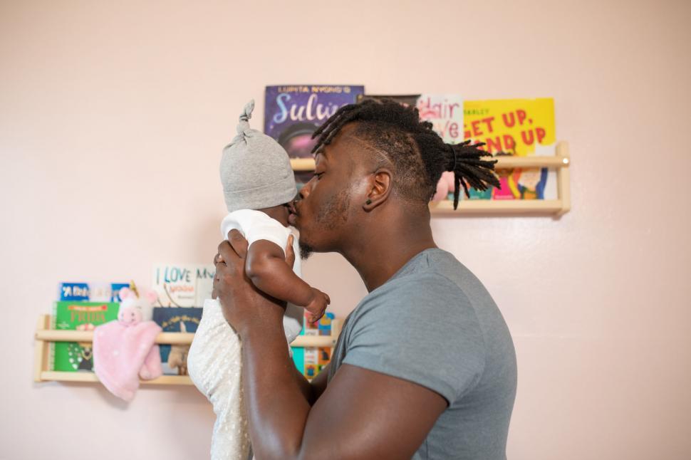 Free Image of Young Father in grey t-shirt Kissing Newborn Baby 