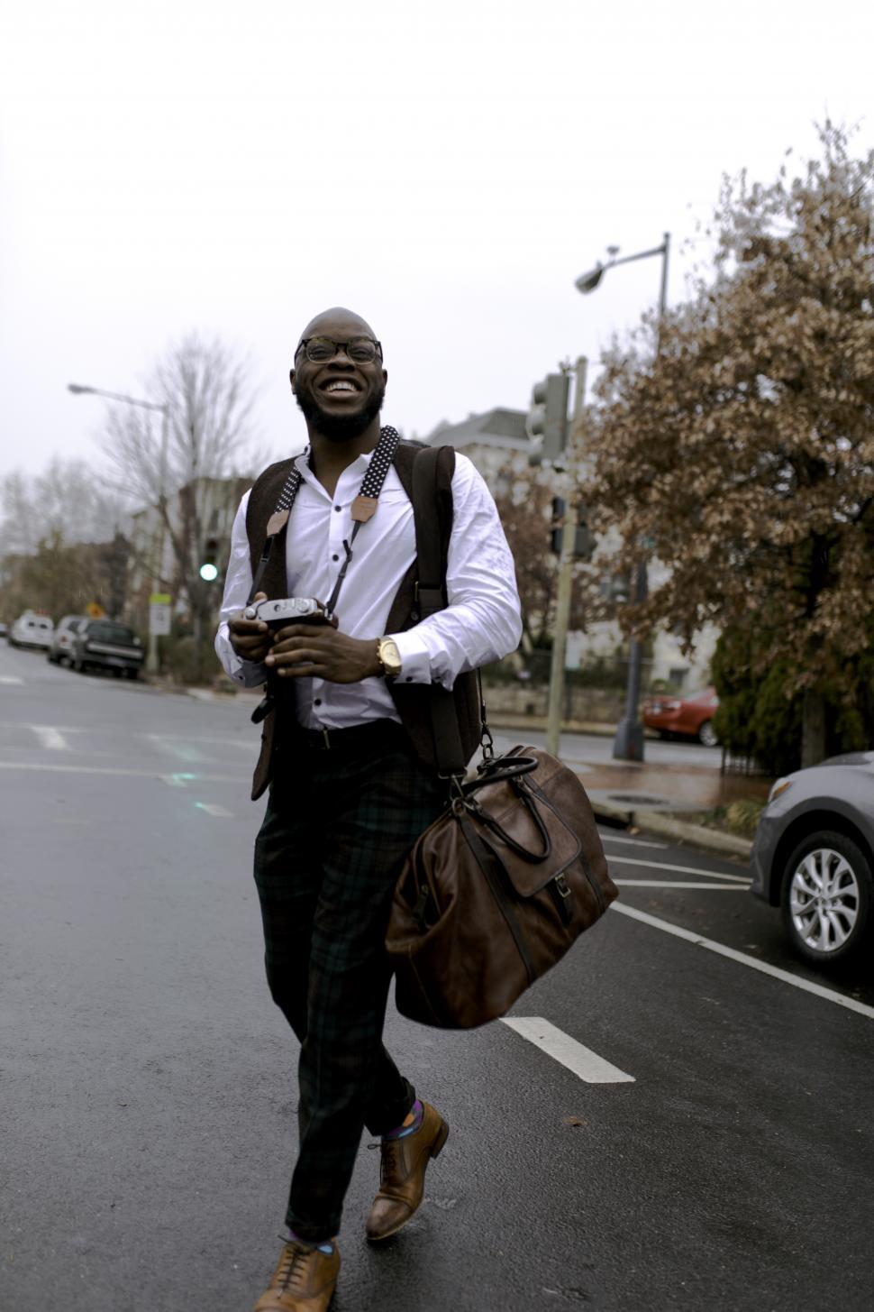 Free Image of Young Man holding a vintage camera and leather bag 