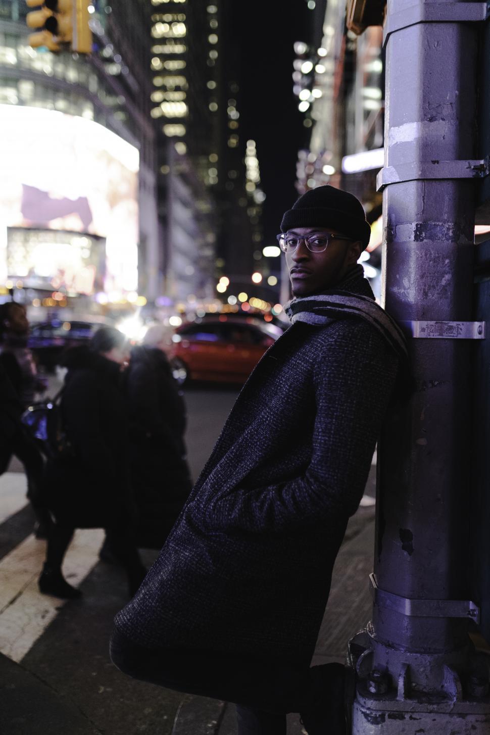 Free Image of Night View of Young Businessman in tweed overcoat on road with people - looking at camera 